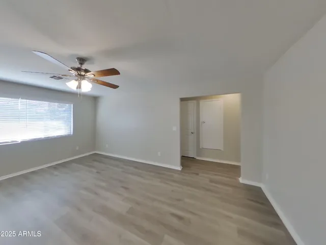a view of wooden floor and a chandelier fan in an empty room