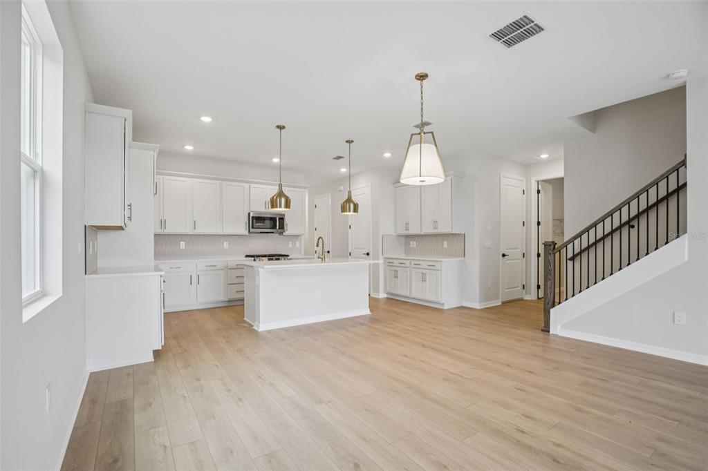 10167 Hidden Hammock Loop Parrish, FL 34221 - Photo 5 of 42 a large white kitchen with kitchen island a sink a center island stainless steel appliances and a cabinets