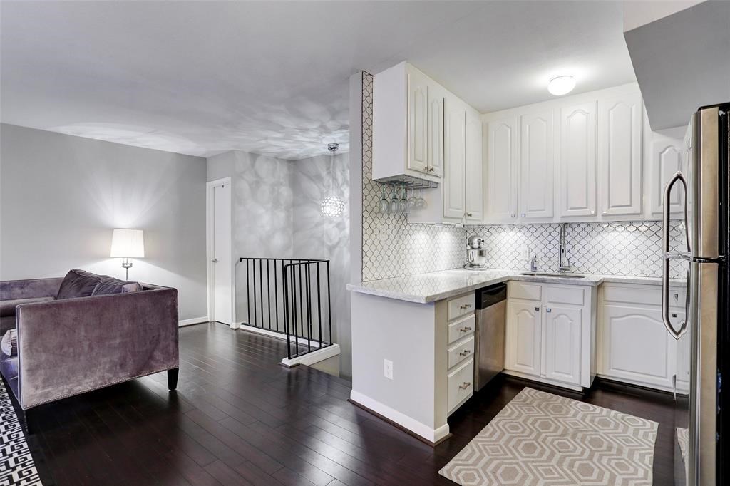 a kitchen with stainless steel appliances granite countertop a refrigerator a sink dishwasher a stove and white cabinets with wooden floor