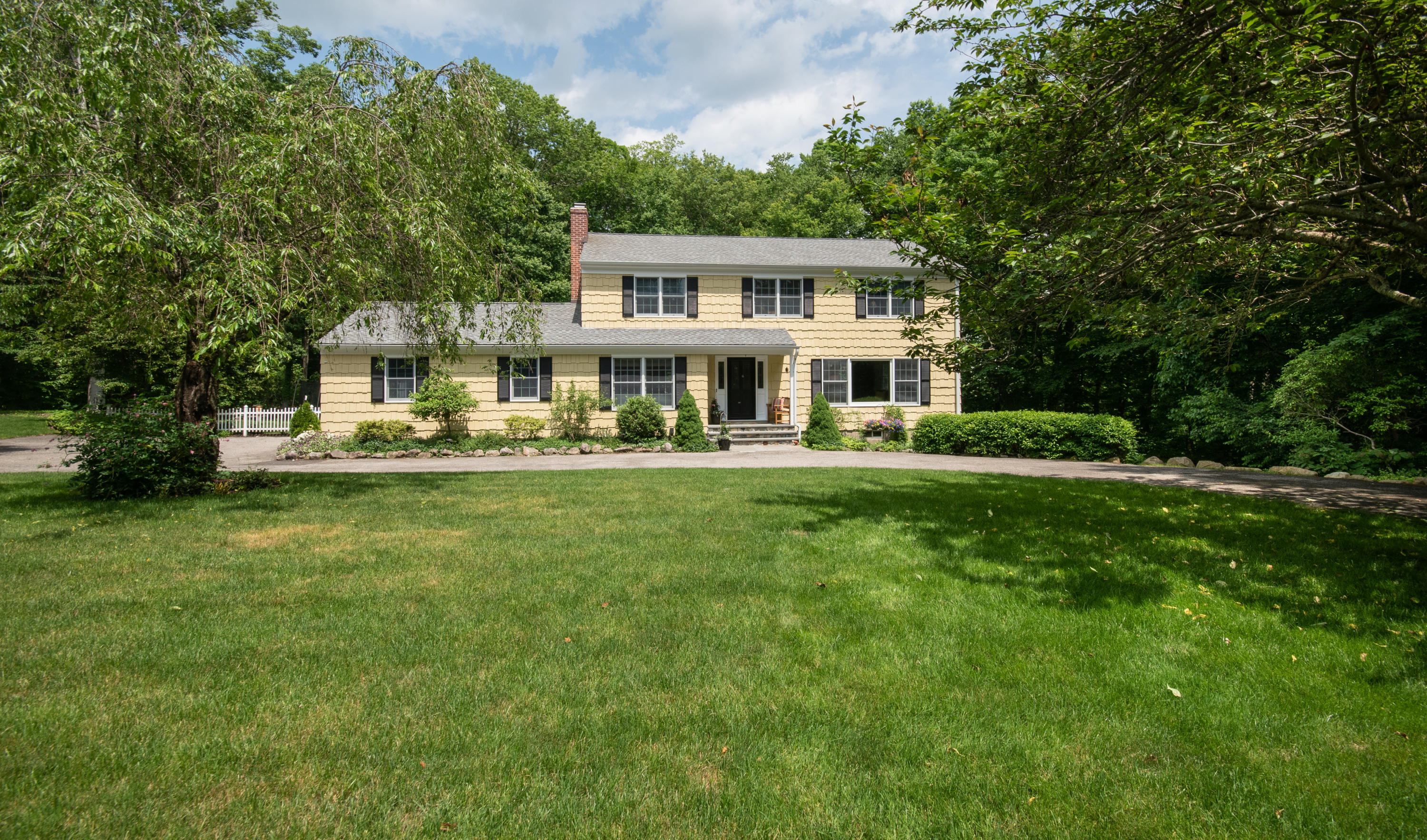 71 Rocky Brook Road New Canaan, CT 06840 - Photo 2 of 28 a front view of a house with a yard table and chairs