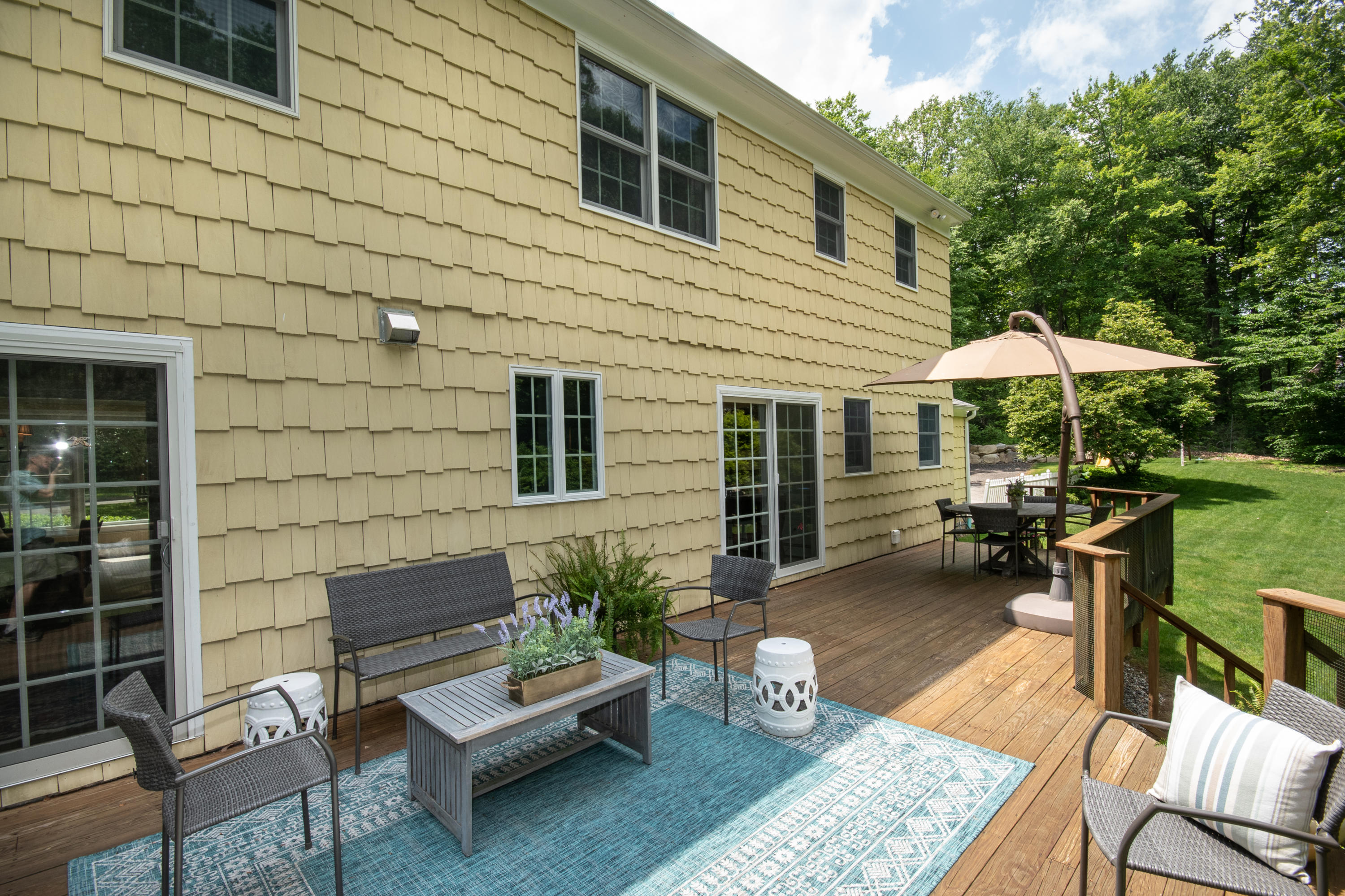71 Rocky Brook Road New Canaan, CT 06840 - Photo 24 of 28 a view of a patio with couches table and chairs under an umbrella
