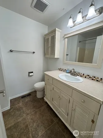 a bathroom with a granite countertop sink a toilet and a mirror