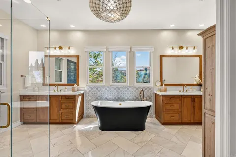 a spacious bathroom with a tub a double vanity sink a mirror and a shower