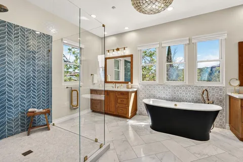 a large spacious bathroom with a tub a double vanity sink a mirror and a shower