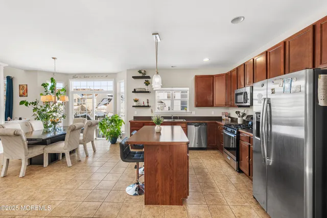 a kitchen with stainless steel appliances granite countertop a refrigerator a sink a stove and chairs