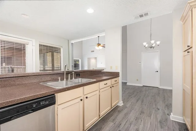 a kitchen with a sink dishwasher and a stove with wooden floor