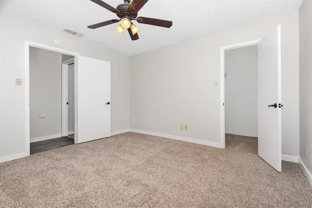 an empty room with closet and a chandelier fan