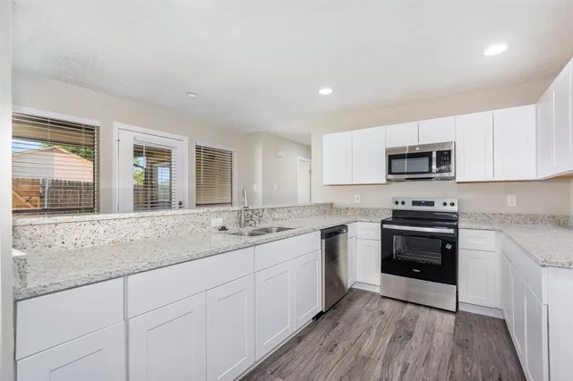 a kitchen with granite countertop white cabinets and black stainless steel appliances