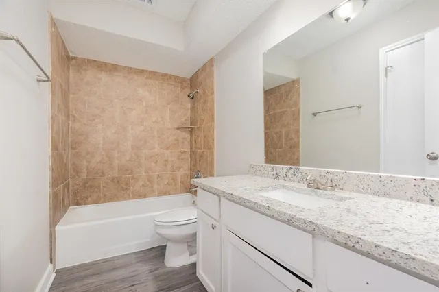 a bathroom with a granite countertop sink a toilet and shower