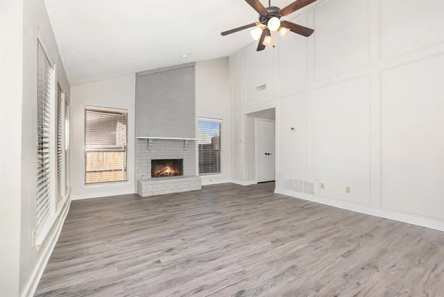 an empty room with wooden floor a ceiling fan and fireplace