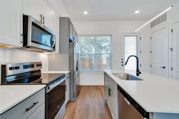 a kitchen with kitchen island a sink appliances cabinets and a window