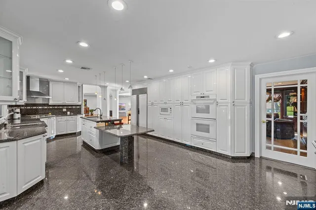 a large white kitchen with stainless steel appliances lots of white cabinets