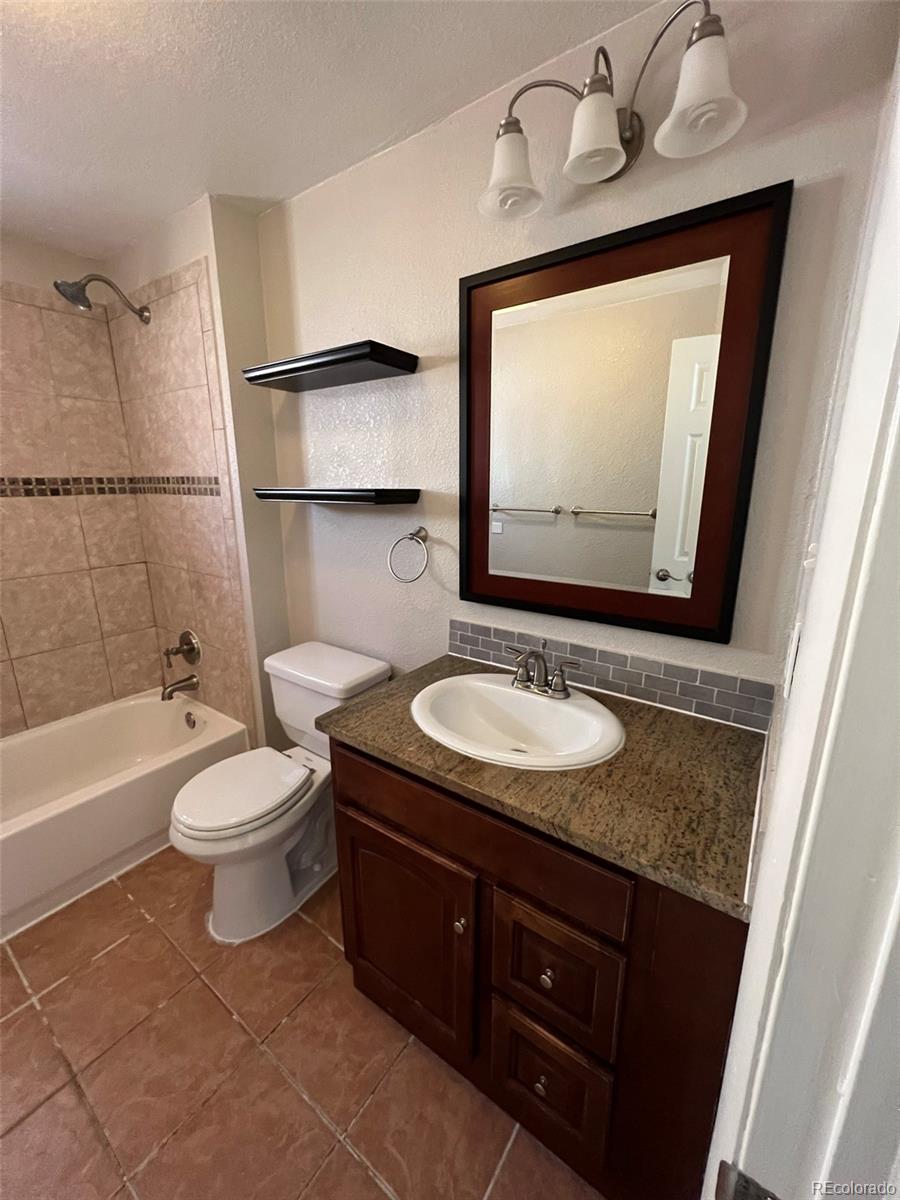 1245 Yates Street Denver, CO 80204 - Photo 12 of 24 a bathroom with a granite countertop sink toilet and mirror