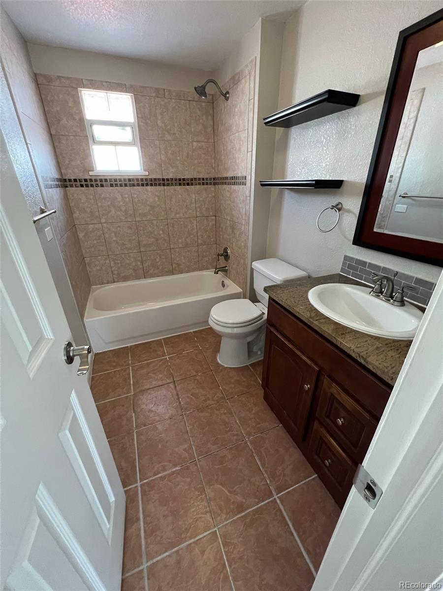1245 Yates Street Denver, CO 80204 - Photo 13 of 24 a bathroom with a granite countertop sink toilet a mirror and shower