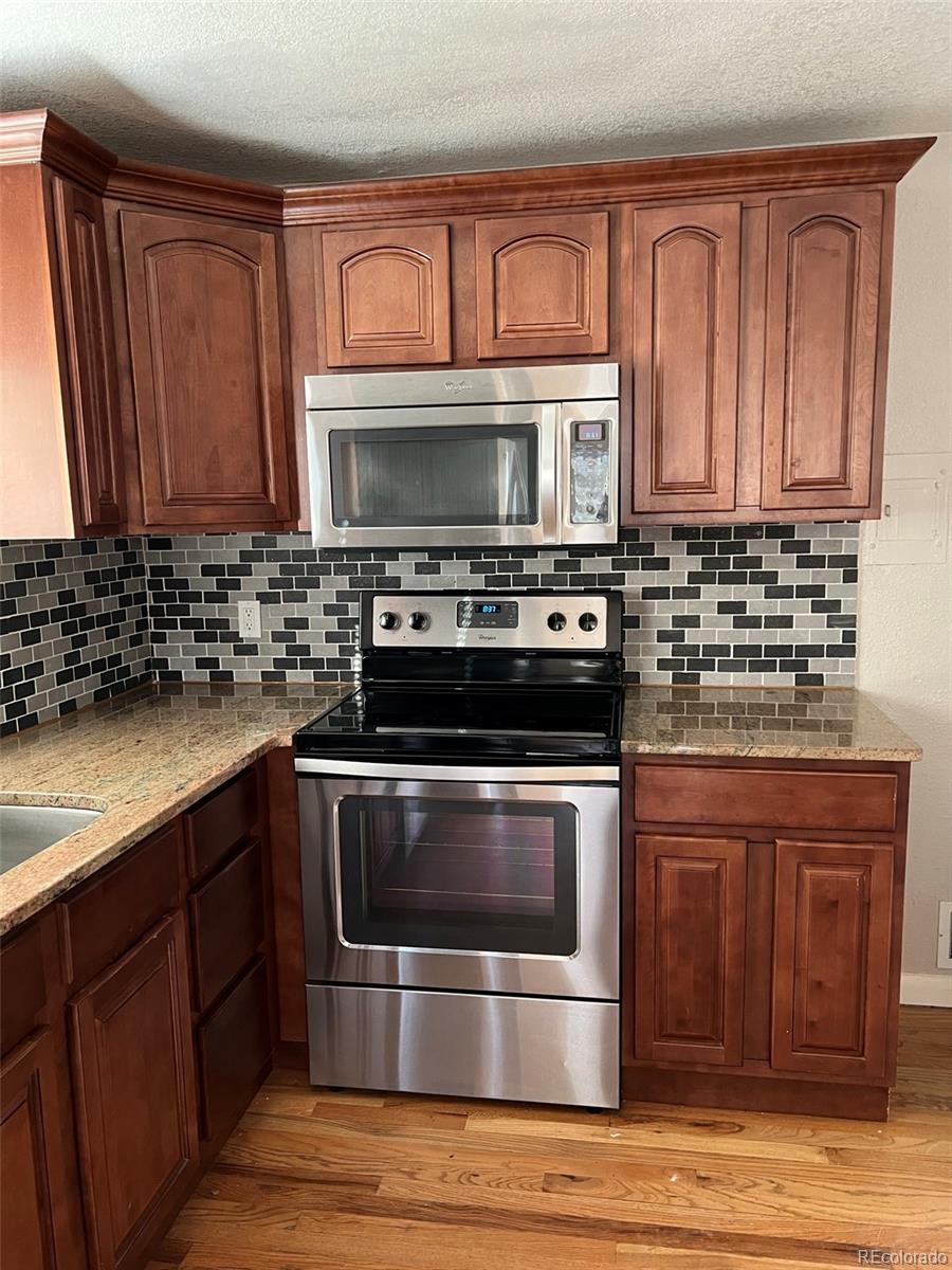 1245 Yates Street Denver, CO 80204 - Photo 3 of 24 a kitchen with stainless steel appliances granite countertop a stove a sink and a microwave
