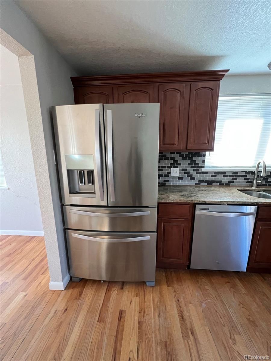 1245 Yates Street Denver, CO 80204 - Photo 5 of 24 a kitchen with wooden floors and stainless steel appliances