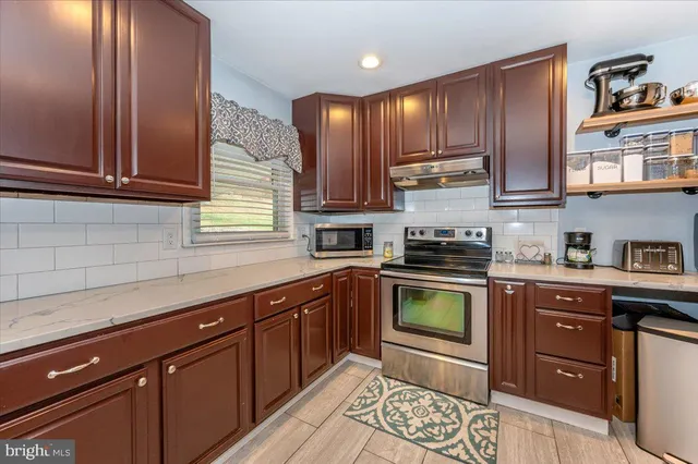 a kitchen with stainless steel appliances granite countertop a stove a sink and a microwave