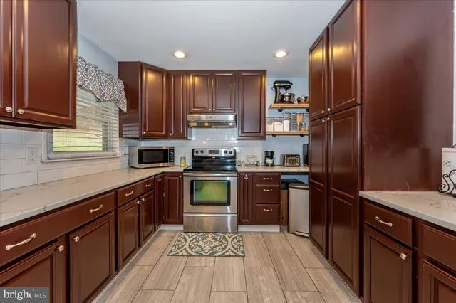 a kitchen with stainless steel appliances granite countertop a refrigerator a sink dishwasher a stove top oven and a refrigerator