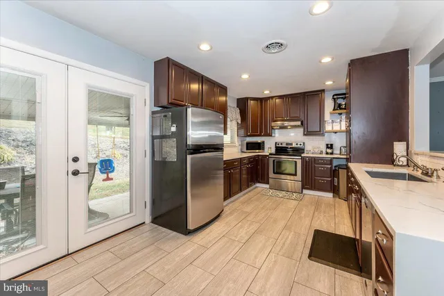 a kitchen with granite countertop a refrigerator a sink a stove top oven and cabinets