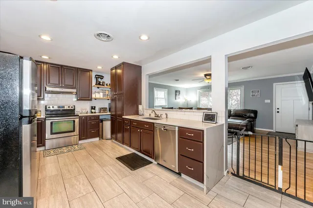 a kitchen with stainless steel appliances kitchen island granite countertop a refrigerator oven a sink dishwasher and white cabinets with wooden floor