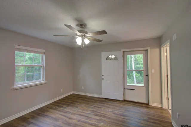 a view of an empty room with a window and wooden floor