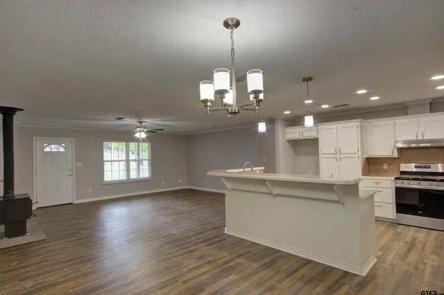 a kitchen with stainless steel appliances granite countertop a stove top oven a sink dishwasher a oven and a dining table with wooden floor