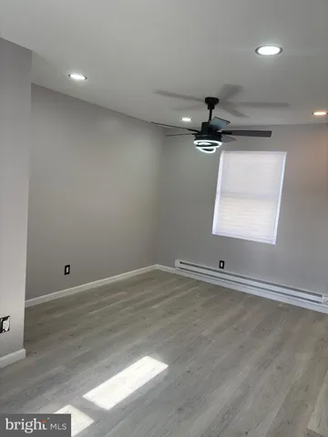 an empty room with wooden floor and a ceiling fan