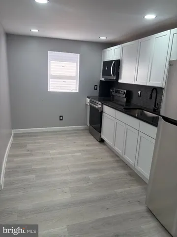 a kitchen with granite countertop white cabinets stainless steel appliances and a sink