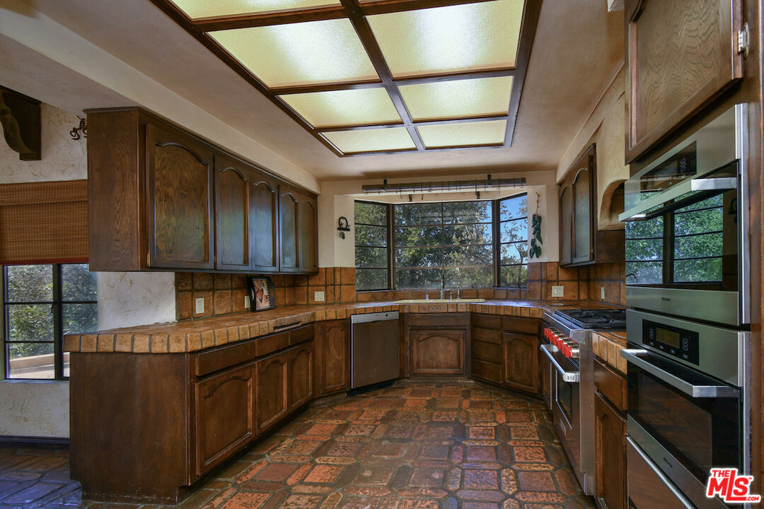 24926 Jim Bridger Road Hidden Hills, CA 91302 - Photo 11 of 28 a kitchen with stainless steel appliances granite countertop sink stove and cabinets