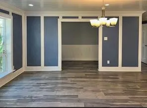 a view of a hallway with wooden floor and chandelier