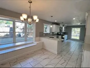 a view of a kitchen with granite countertop a large window and a chandelier