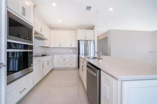 a large kitchen with stainless steel appliances a sink and cabinets