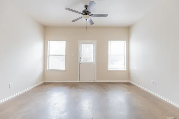 an empty room with wooden floor fan and windows