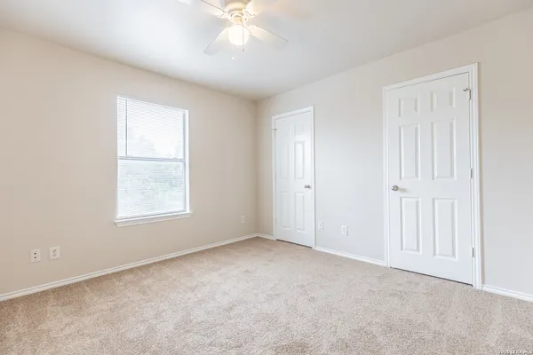 an empty room with windows and fan