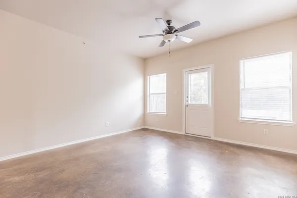 an empty room with windows and fan