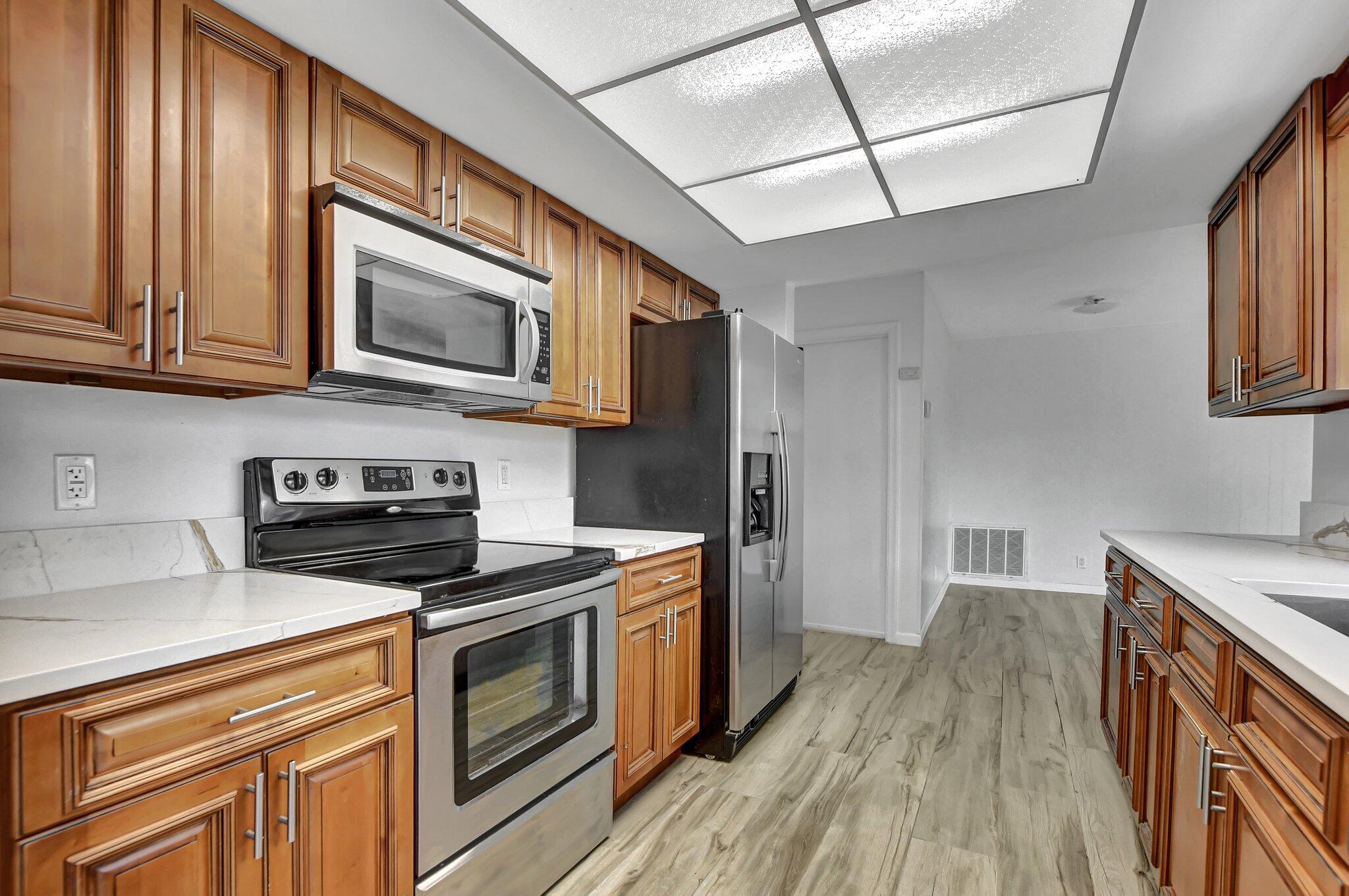 254 Northwest 11th Avenue Boca Raton, FL 33486 - Photo 18 of 66 a kitchen with stainless steel appliances granite countertop wooden cabinets stove top oven and sink