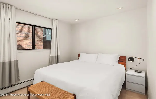 a bedroom with a bed a window and lamp