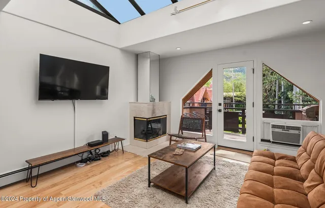 a living room with furniture a flat screen tv and a floor to ceiling window