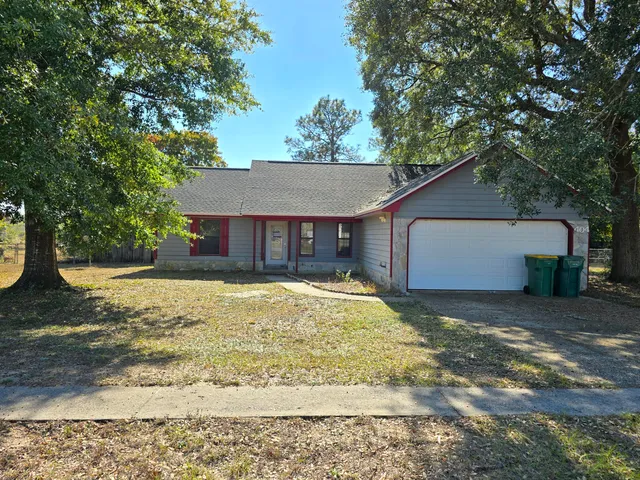 a view of a house with a yard and large tree