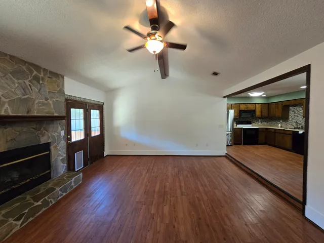 a view of empty room with wooden floor and fireplace
