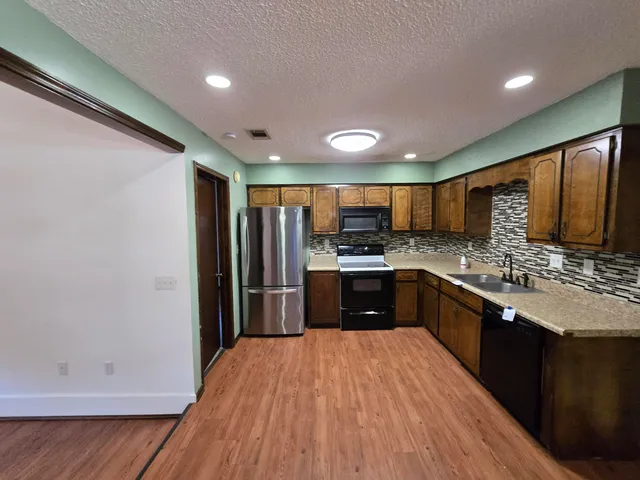 a kitchen with stainless steel appliances kitchen island granite countertop a refrigerator and a stove top oven