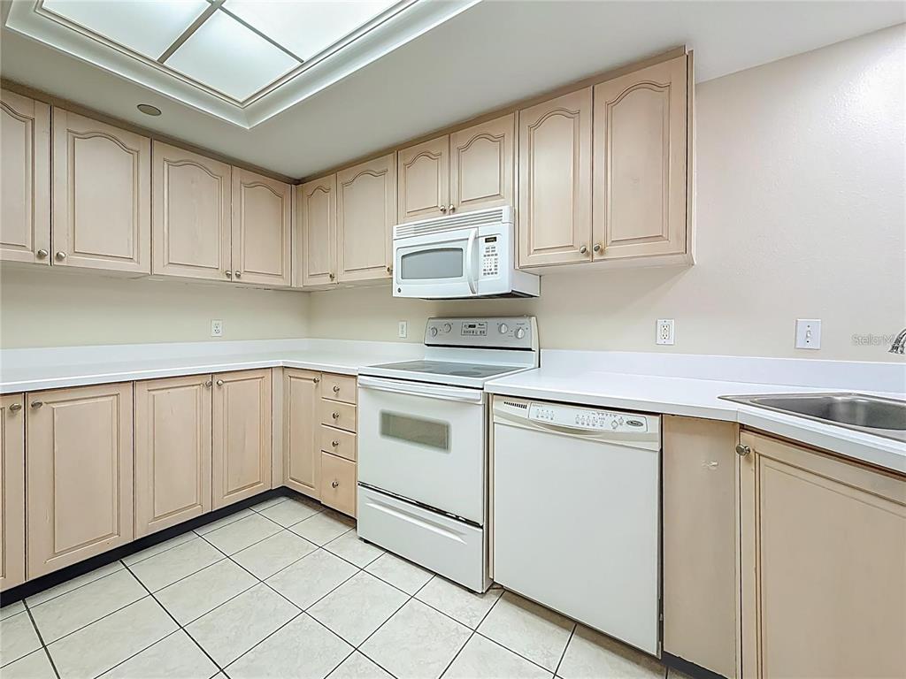399 150th Avenue, Unit 218 Madeira Beach, FL 33708 - Photo 21 of 84 a kitchen with white cabinets and white appliances