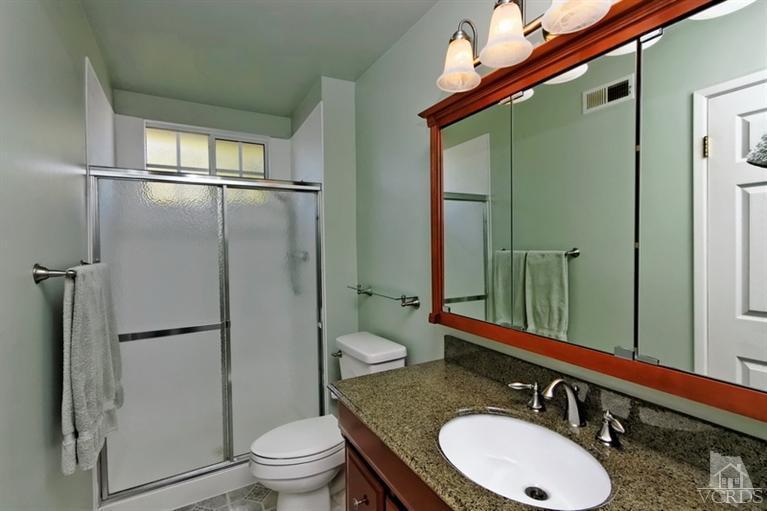 4553 Alpine Street Simi Valley, CA 93063 - Photo 12 of 25 a bathroom with a granite countertop sink toilet a mirror and shower
