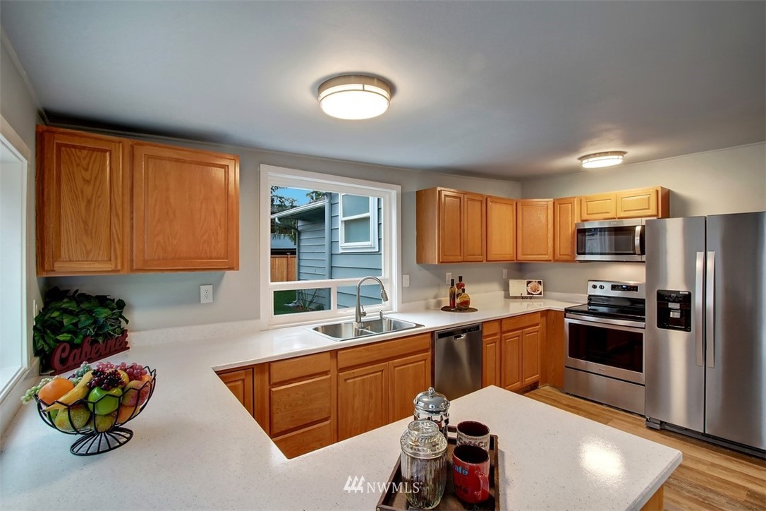 4401 Northeast 10th Street Renton, WA 98059 - Photo 6 of 18 a kitchen with stainless steel appliances granite countertop a sink dishwasher stove and refrigerator with wooden floor