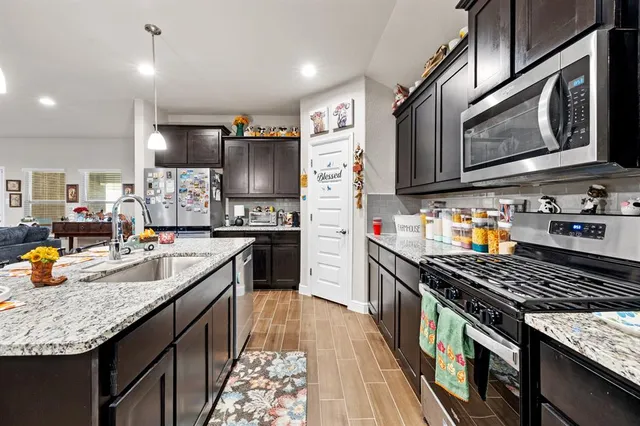 a kitchen with stainless steel appliances granite countertop a stove a sink dishwasher and cabinets with wooden floor