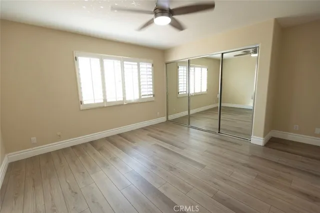 an empty room with wooden floor fan and windows