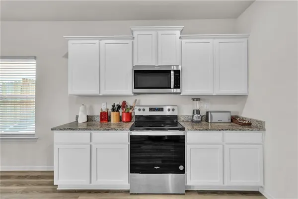 a kitchen with white cabinets and appliances