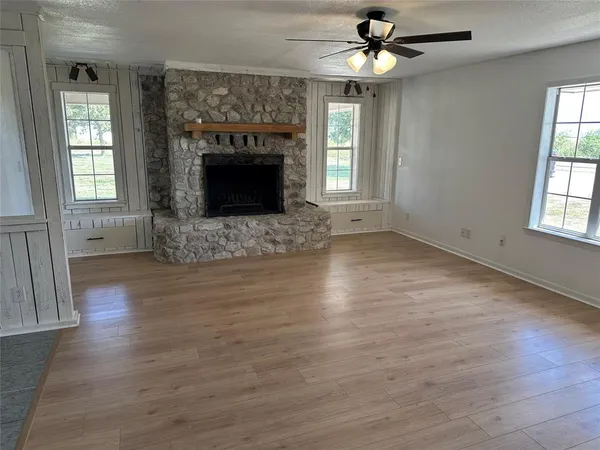 an empty room with wooden floor fireplace and windows