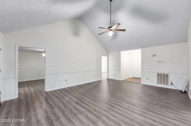 a view of empty room with wooden floor and ceiling fan