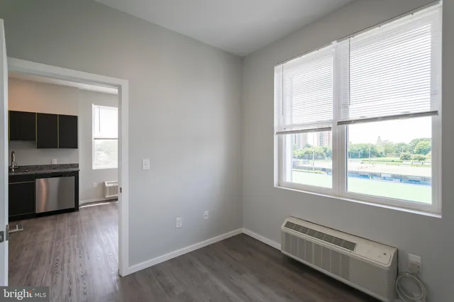 a view of an empty room with a window and wooden floor